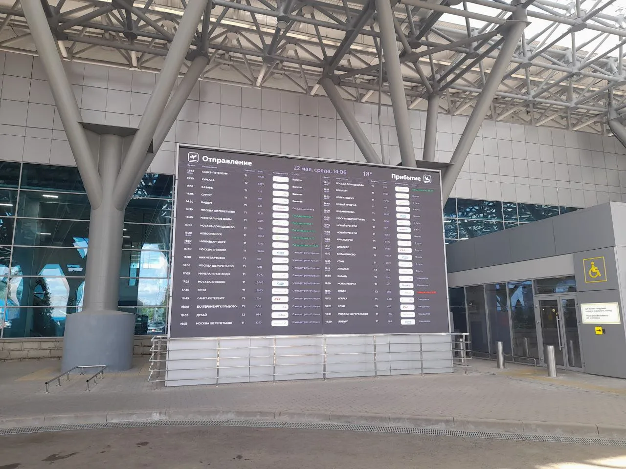 The same flight information board in the local language on the terminal LED wall, showing the SpinetiX player rendering bilingual departures and arrivals from one shared feed